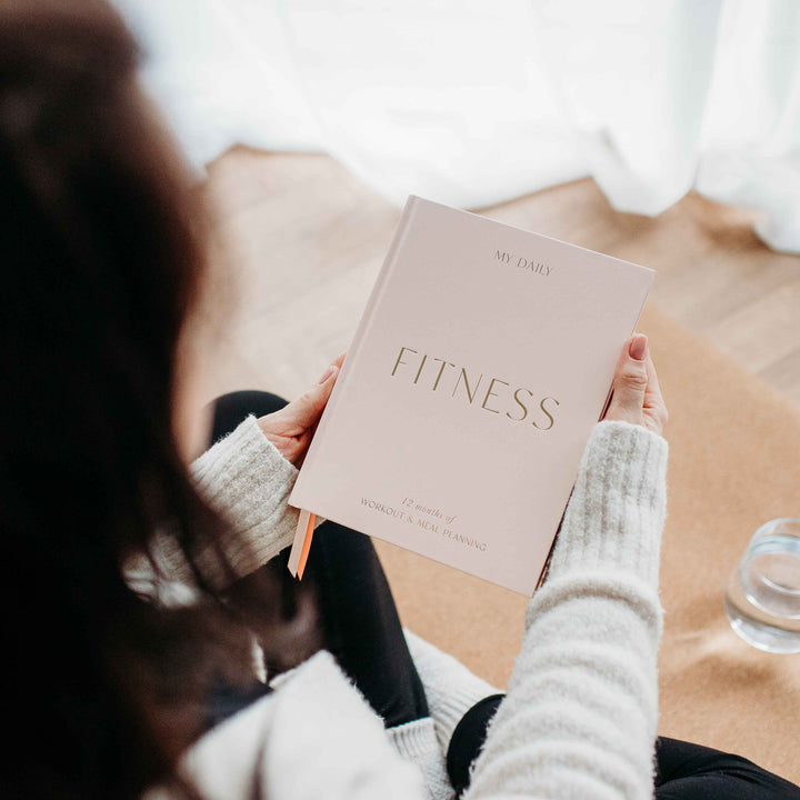 Female athlete journaling in her Fitness Log Book after a workout.