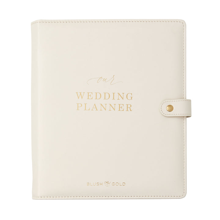 Close-up of an ivory leather wedding planner binder with gold foil "Our Wedding Planner" lettering and snap closure
