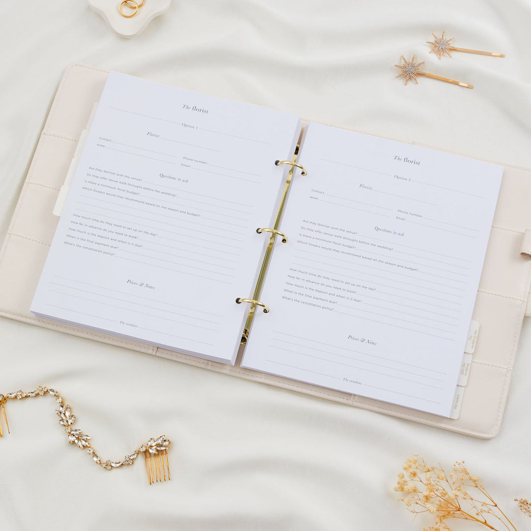 Open wedding planner binder showing two florist comparison pages with vendor contact fields and questions to ask, styled with bridal hair accessories flatlay
