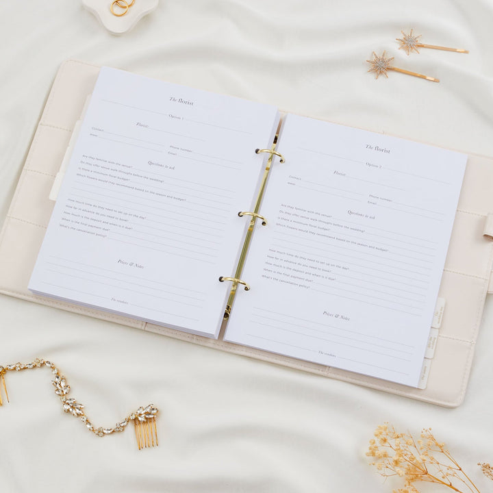 Open wedding planner binder showing two florist comparison pages with vendor contact fields and questions to ask, styled with bridal hair accessories flatlay