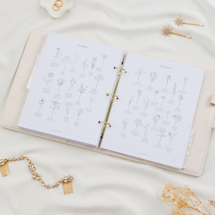 Open wedding planner binder showing a double page illustrated guide to wedding flowers with named line drawings of varieties including roses, dahlias and hydrangeas