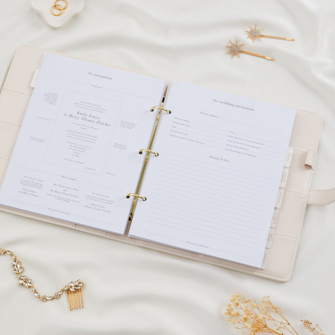 Open wedding planner binder showing a wedding invitations section with wording examples and a stationer details form