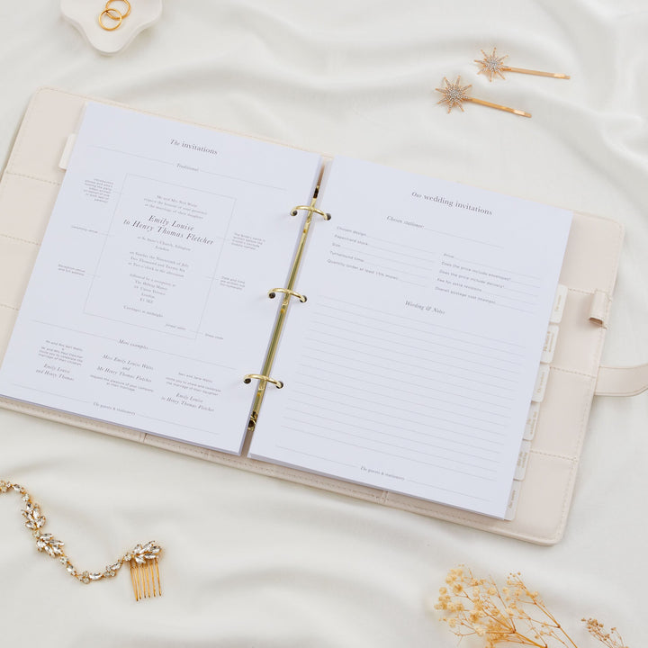 Open wedding planner binder showing a wedding invitations section with wording examples and a stationer details form