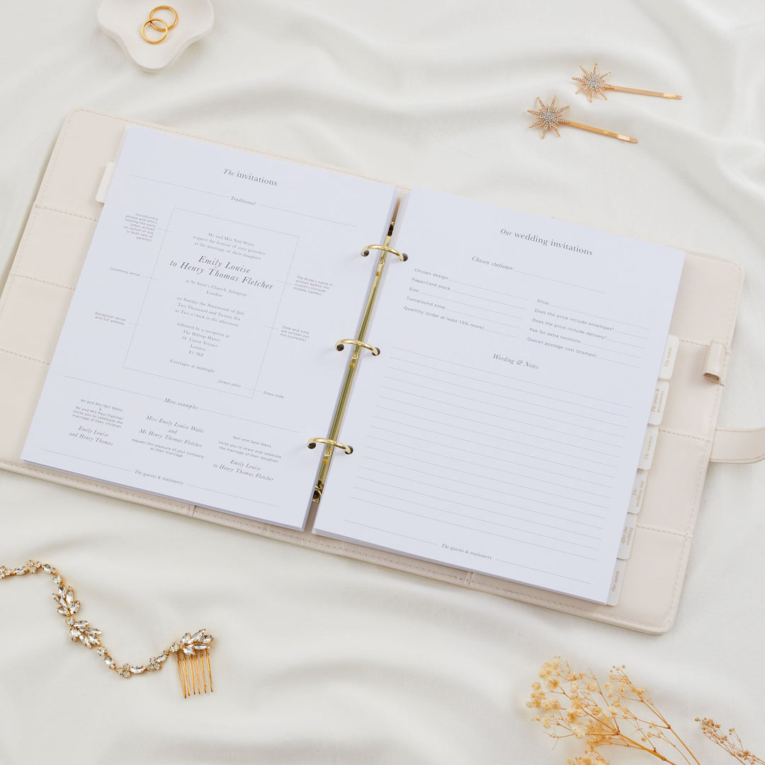 Open wedding planner binder showing a wedding invitations section with traditional wording examples on the left and a stationer details form on the right