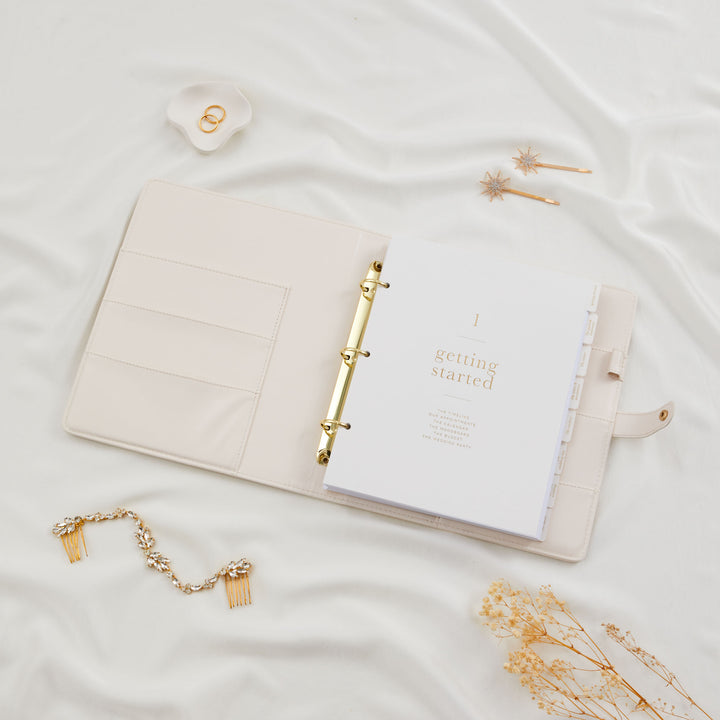 Open ivory wedding planner binder showing the getting started section divider with gold ring hardware and interior card pockets