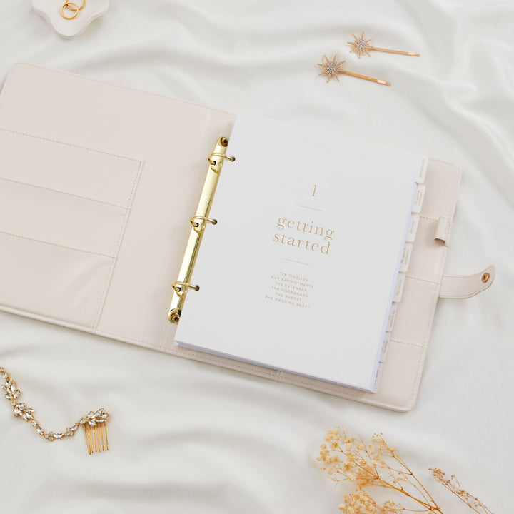 Open wedding planner binder with gold ring binder and bridal hair accessories flatlay