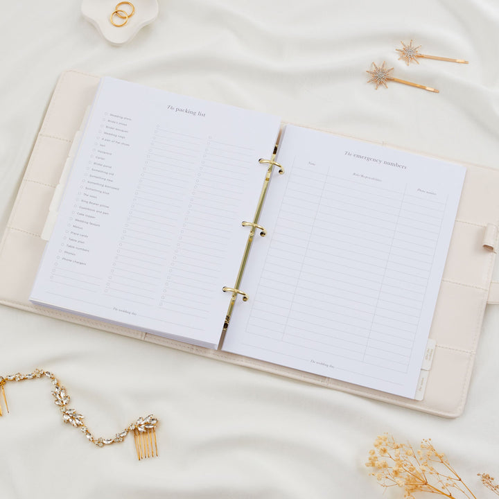 Open wedding planner binder showing a wedding day packing list checklist on the left and an emergency contacts page with name, role and phone number columns on the right