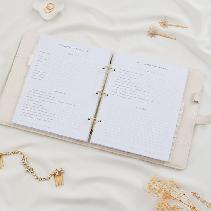 Open wedding planner binder showing detailed reception venue research pages with contact fields and extensive questions to ask covering catering, music and cancellation policy