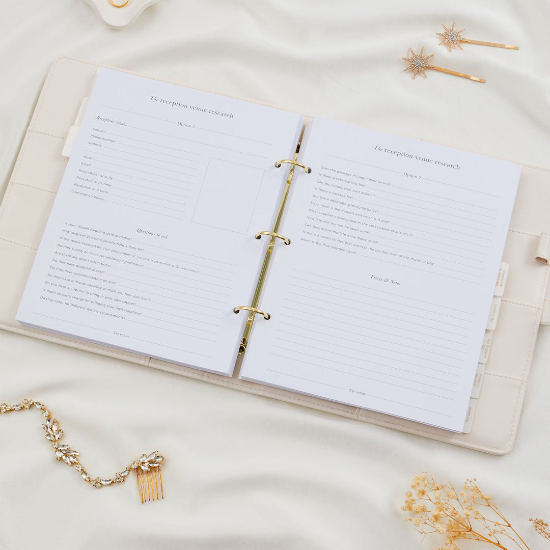 Open wedding planner binder showing two reception venue research pages with contact fields and detailed questions to ask the venue