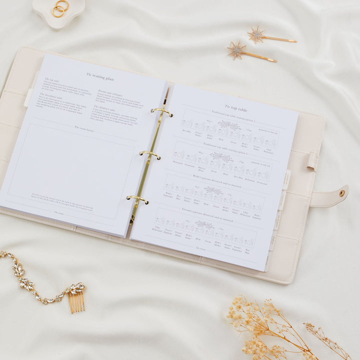 Open wedding planner binder showing a seating plan section with top table layout diagrams and room layout page