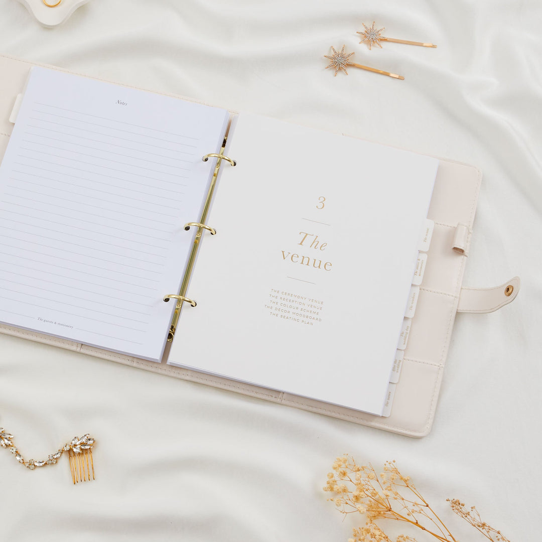 Open wedding planner binder showing the venue section divider with gold foil text and all labelled gold foil tabs clearly visible on the right edge