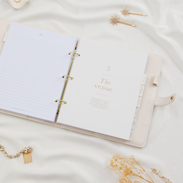 Open wedding planner binder showing the venue section divider with gold foil text and all labelled gold foil tabs clearly visible on the right edge