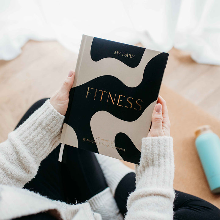 Woman filling out her daily workout planner after morning run