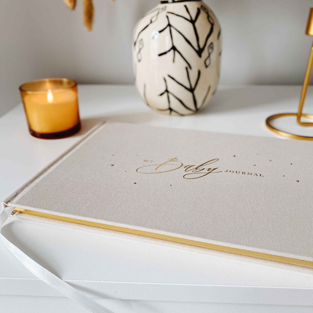 Close-up of the gold gilt edging on the pages of the baby memory book, showcasing the luxurious and shiny finish against the white pages.